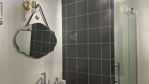 Une salle de bain avec un lavabo blanc, un miroir et un espace douche.
