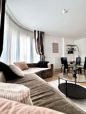 Una sala de estar moderna con un sofá, una mesa de centro de vidrio y un comedor con sillas y una mesa.