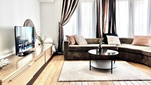 A modern living room with a curved sofa, a coffee table, and a flat-screen TV on a wooden floor. - Peaceful 2 minutes European Parliament (Brussels)