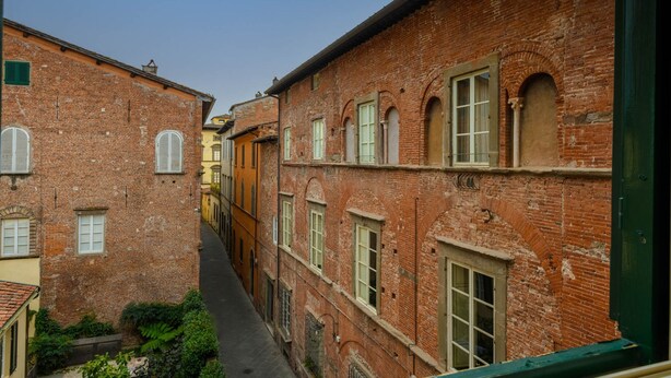 A narrow alley between buildings with brick facades and arched windows. - Orsucci Palace in Lucca (Lucca)