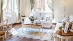 A spacious living room with a white sofa, a wooden coffee table, and a chandelier. - Orsucci Palace in Lucca (Lucca)