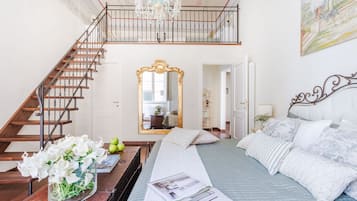 Un dormitorio con una cama, una escalera de madera, un espejo grande y una araña.