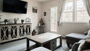 A living room with a TV, a cabinet, a table, and a sofa. - Explore, Relax, Repeat | Riverside Views | Eagle (Eagle)