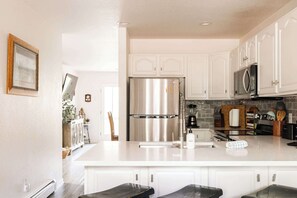 A modern kitchen with white cabinets, stainless steel appliances, and a central island. - Explore, Relax, Repeat | Riverside Views | Eagle (Eagle)