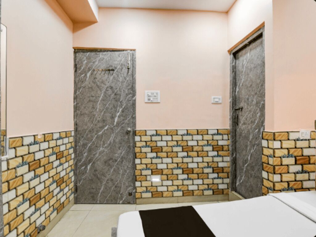 Una habitación con dos puertas, un muro con azulejos y una cama.