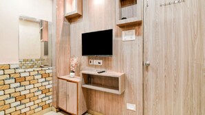Une pièce avec un mur orné d’un motif en briques, un meuble en bois sur lequel est posée une télévision à écran plat, et une porte dotée d’une poignée.