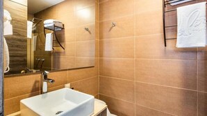 Une salle de bain moderne avec un grand miroir, un lavabo blanc et un porte-serviettes.