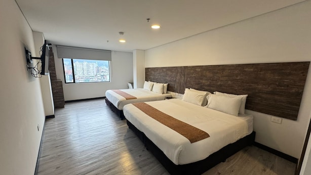 Une chambre d’hôtel avec deux lits, une grande fenêtre donnant sur la ville et un plancher en bois.