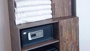 Un placard comprenant un espace pour suspendre des vêtements, un espace pour ranger des serviettes pliées et un mini-réfrigérateur intégré.