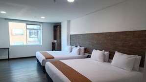 Une chambre d’hôtel avec deux lits, une grande fenêtre et une tête de lit en bois.