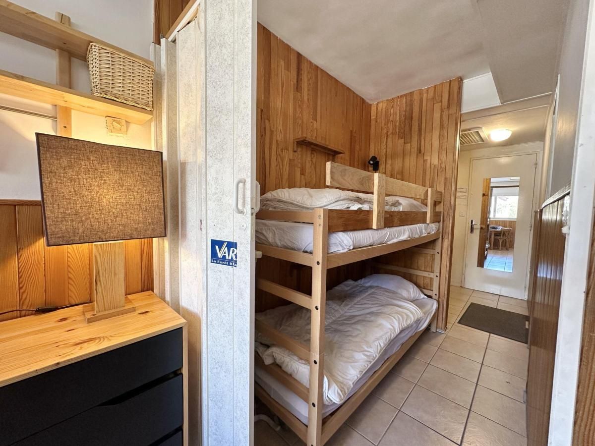 A bunk bed room with a wooden headboard, a small desk with a lamp, and a wall-mounted TV.