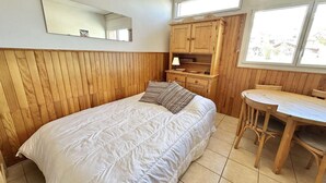 A bedroom with a bed, wooden paneling, a desk, and a chair.