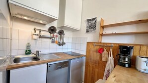 A compact kitchen with white cabinets, a dishwasher, a coffee maker, and a toaster.