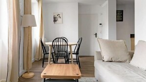 A modern living room with a wooden coffee table, a sofa, a dining table with chairs, and a floor lamp.