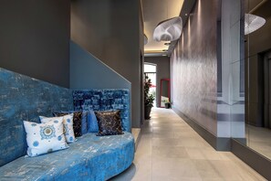 A modern interior with a blue sofa, a large mirror, and a hallway leading to an outdoor area. - Fortyfive Squared (Rome)
