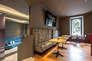A modern bar area with a sofa, tables, and chairs, a large window with a view, and a security camera on the ceiling. - Fortyfive Squared (Rome)
