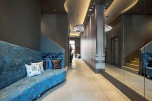 A modern interior with a blue sofa, a glass wall, and a staircase. - Fortyfive Squared (Rome)