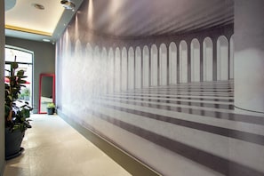 A hallway with a patterned wall, potted plants, and a red-framed mirror. - Fortyfive Squared (Rome)
