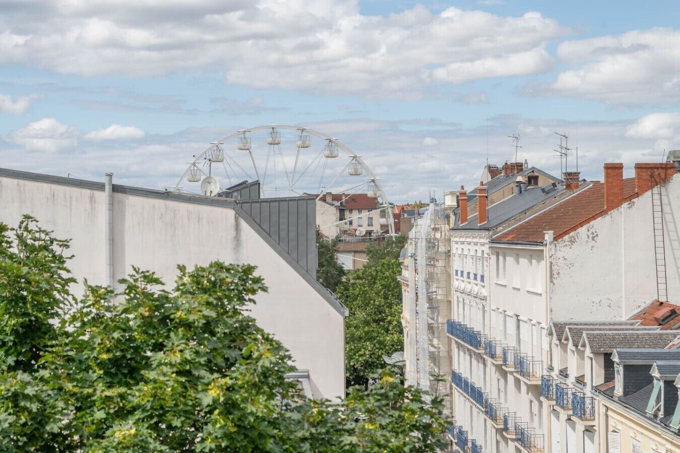 Un paisaje urbano con una noria al fondo, rodeado de edificios residenciales con balcones.