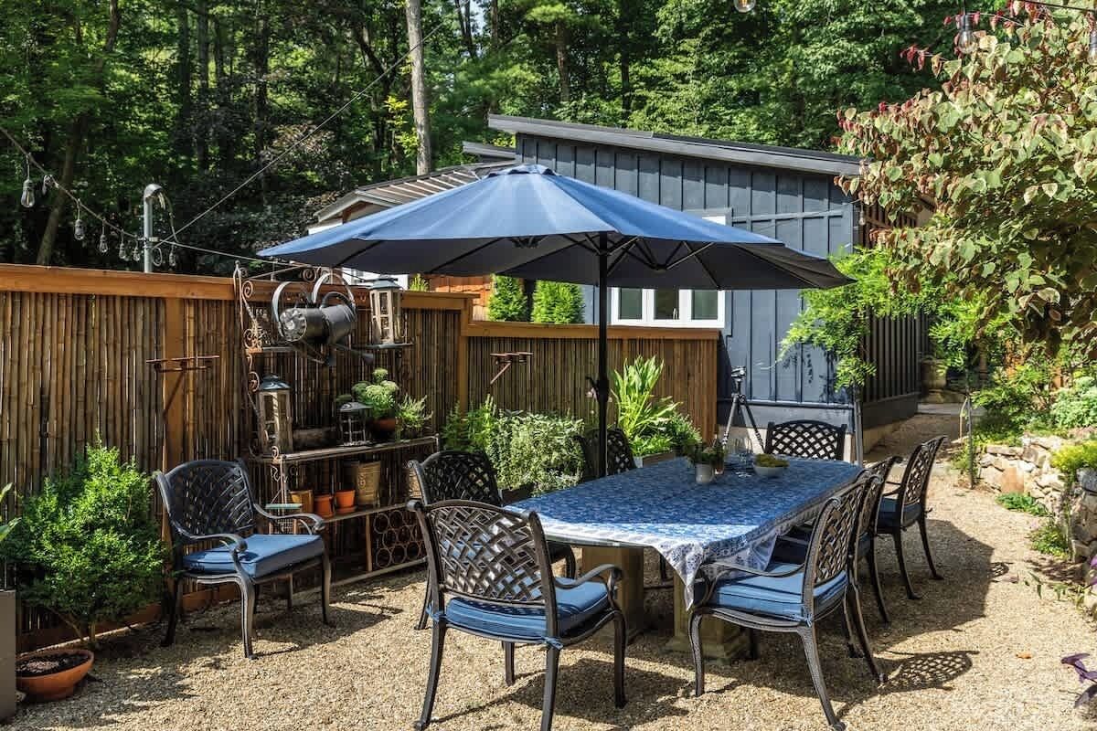 A patio with a table and chairs, surrounded by a wooden fence and potted plants.