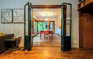 An open doorway leading to a dining area with a wooden table and chairs, a ceiling fan, and a view of the outdoors.