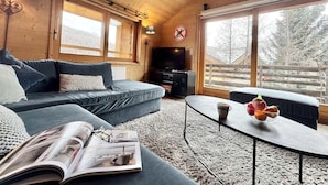 A cozy cabin interior with a sofa, a coffee table with fruit, and a fireplace.