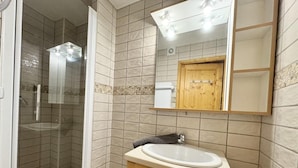 A bathroom with a glass-enclosed shower, a wooden vanity with a sink, and a mirror above the vanity.
