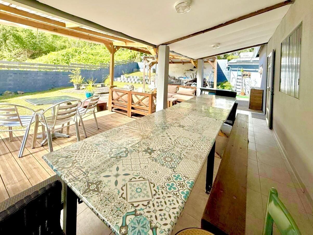 Une terrasse couverte avec une table à motifs, des chaises et une vue sur le jardin arrière.