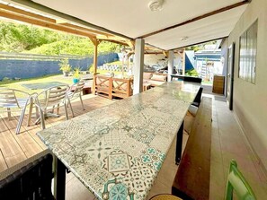 Un patio techado con una mesa y sillas estampadas, y vistas al jardín trasero.