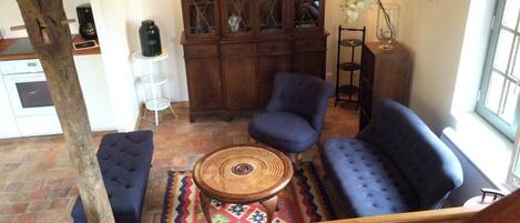 Un salon chaleureux avec un canapé bleu, un meuble en bois et un tapis à motifs.