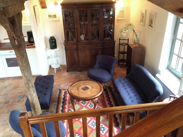 Uma sala de estar aconchegante com um sofá azul, um armário de madeira e um tapete estampado.