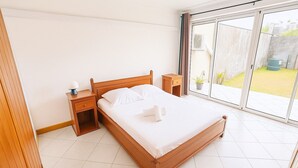 A bedroom with a wooden bed, a nightstand, a bedside table, and a large window with a view of a garden. - Vulcano House, Nature getaway La Plaine des Cafres (La Plaine des Cafres)