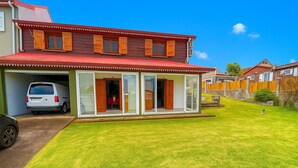 Una casa de dos pisos con techo rojo, garaje y césped cuidado.