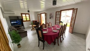 A dining area with a table set for four, surrounded by chairs, a television, and a sofa. - Vulcano House, Nature getaway La Plaine des Cafres (La Plaine des Cafres)