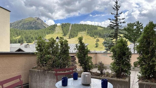 A balcony with a round table, four blue mugs, and a white mug.