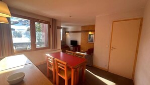 A compact room with a wooden dining table and chairs, a small kitchenette, and a single door. - 250m from ski slopes, 4th floor, view ski slopes, swimming pool, balcony, ski locker, 34m² (La Plagne)
