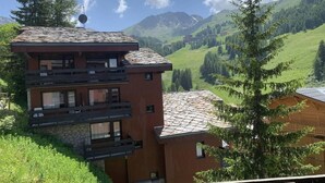 A multi-story building with balconies, set against a mountainous backdrop. - 250m from ski slopes, 4th floor, view ski slopes, swimming pool, balcony, ski locker, 34m² (La Plagne)