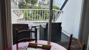A balcony with a table and chairs, overlooking a residential area with houses and trees. - Appartement des iles (Quiberon)