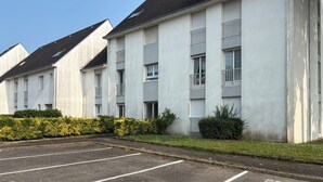 A row of white apartment buildings with a parking lot in front. - Appartement des iles (Quiberon)