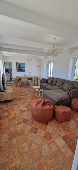 A spacious living area with a large sofa, a dining table, and a kitchen in the background. - House near wild coast and castle (Quiberon)