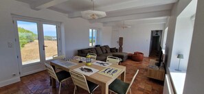 A spacious living area with a dining table, sofa, and a view of the outdoors. - House near wild coast and castle (Quiberon)