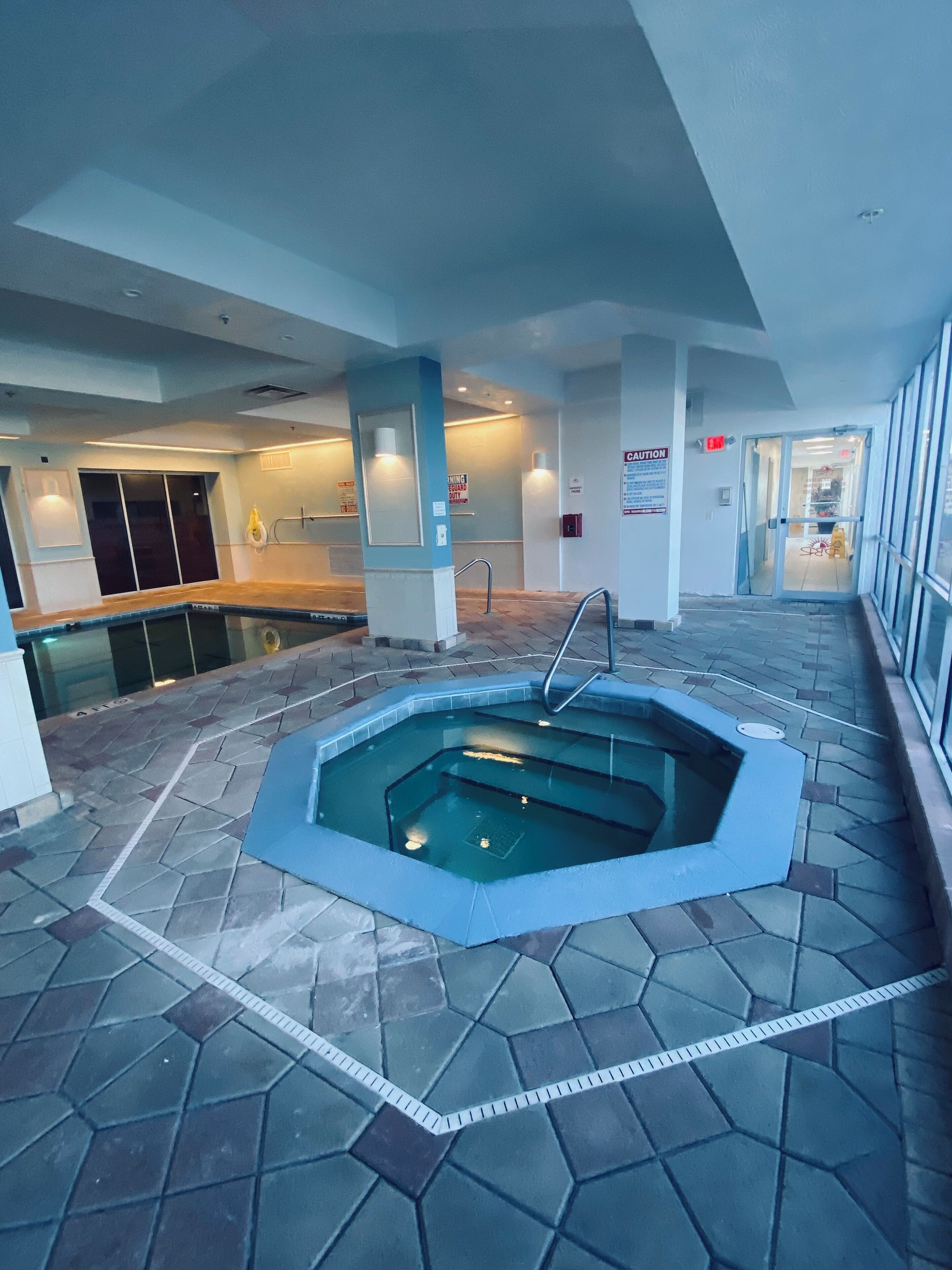 Ein Schwimmbecken mit geometrischem Design, umgeben von gefliestem Boden und Wänden.