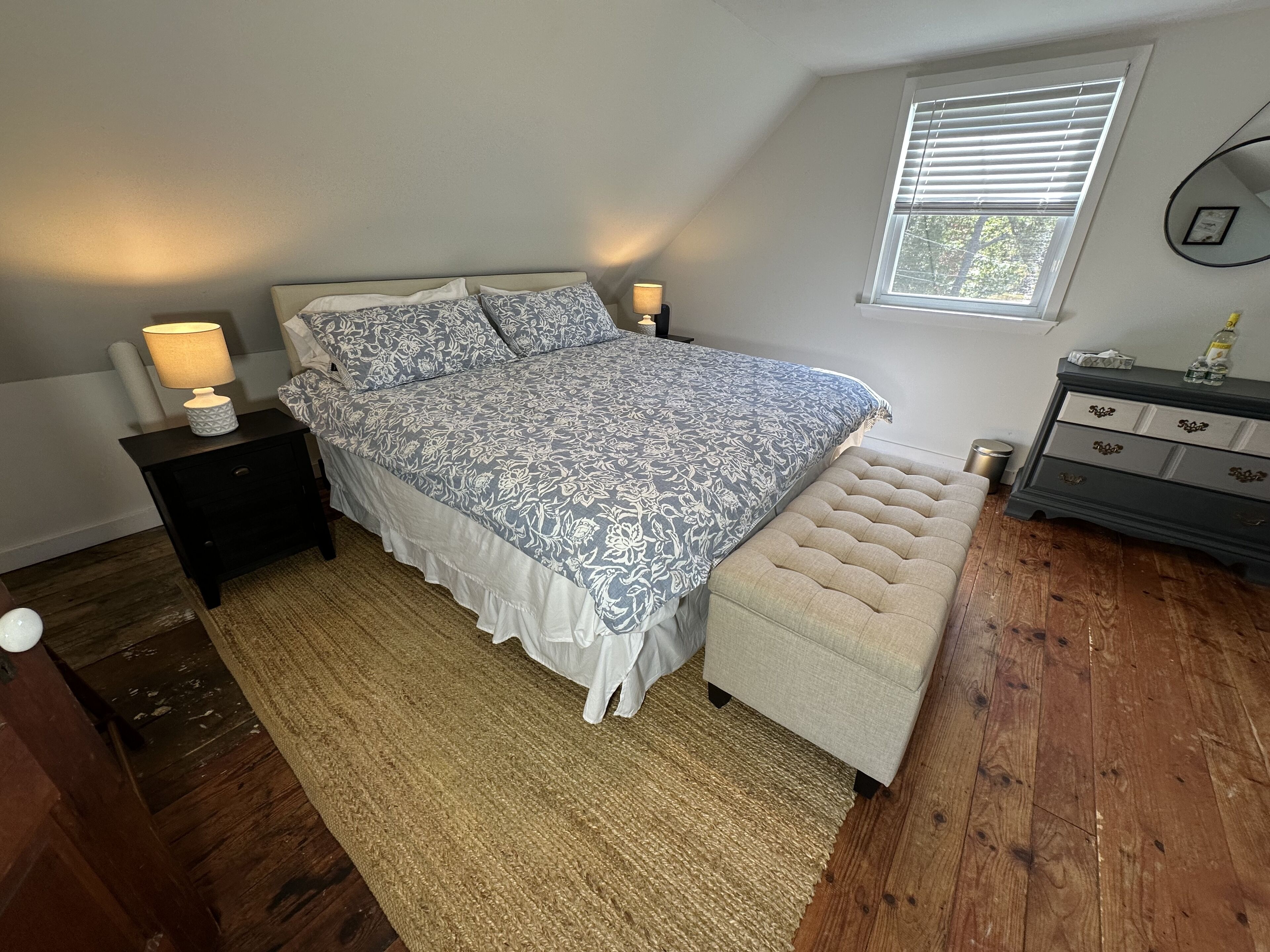 Een slaapkamer met een bed, nachtkastjes, een dressoir en een raam.