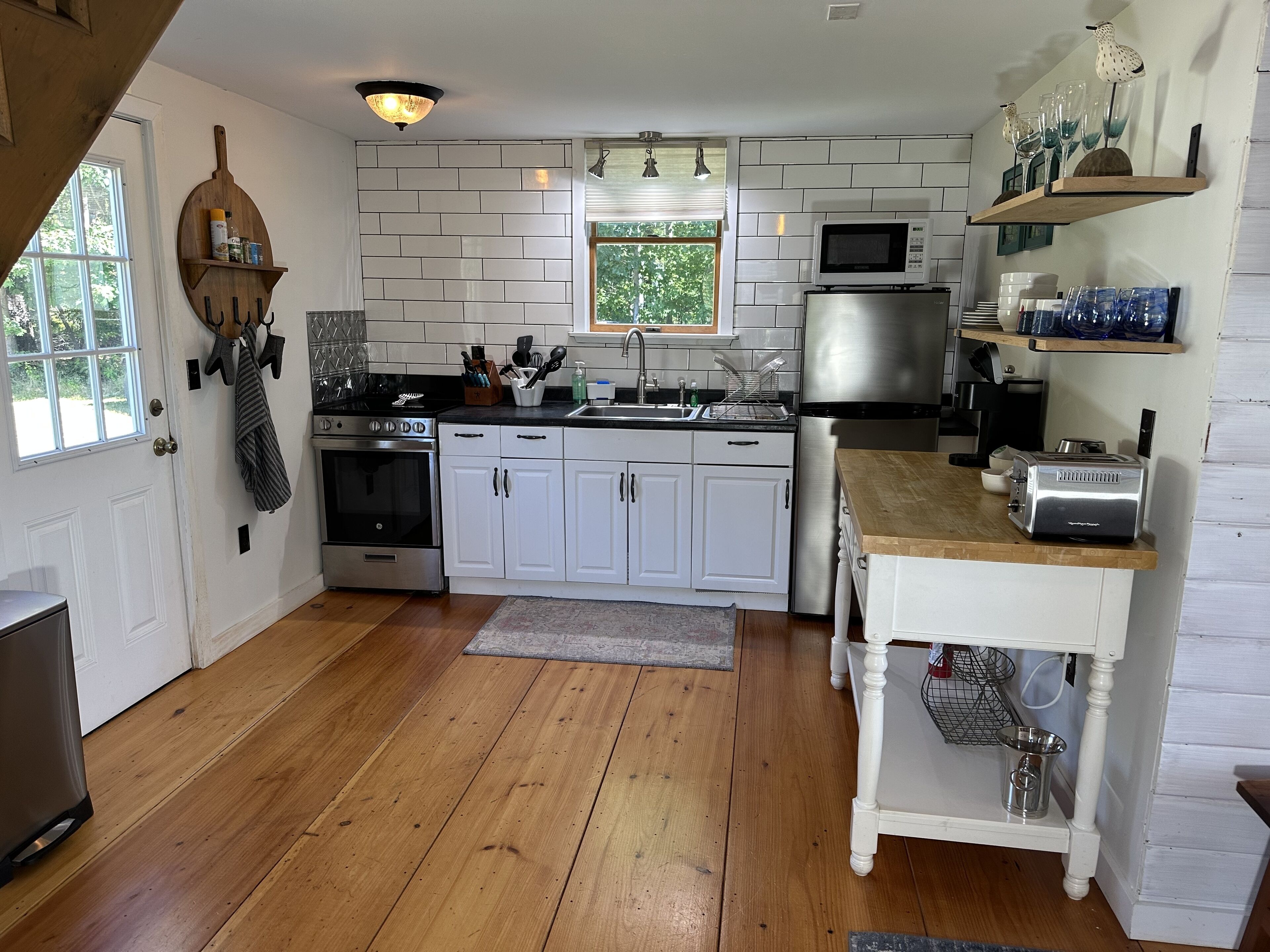 Een keuken met witte kastjes, een roestvrijstalen koelkast, een magnetron en een broodrooster.
