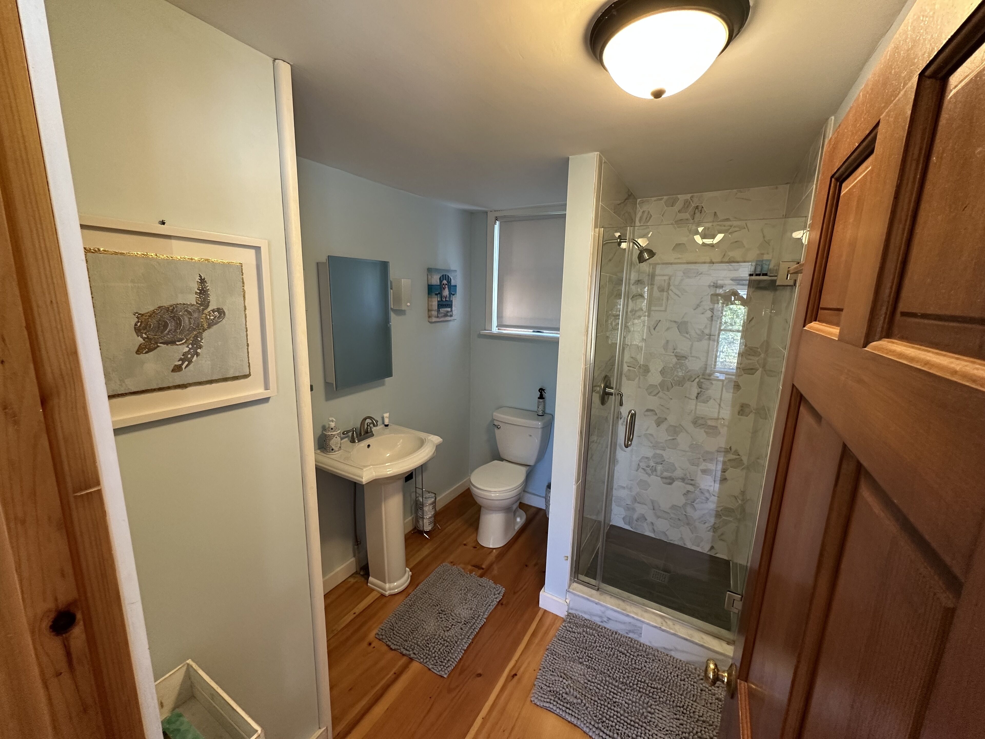 A bathroom with a pedestal sink, toilet, and glass shower enclosure.