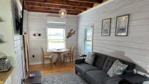 A cozy living room with a gray sofa, wooden chairs, a small table, and a rug. - Ocean View Dog Friendly Cottage 4-min to Kennebunkport (Kennebunk)