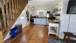 A kitchen with wooden floors, white cabinets, a stainless steel refrigerator, and a wooden staircase. - Ocean View Dog Friendly Cottage 4-min to Kennebunkport (Kennebunk)