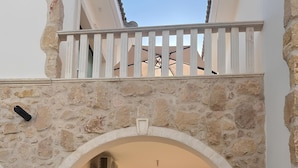 Una entrada arqueada con fachada de piedra, un camino de acceso con portones y vista al interior.
