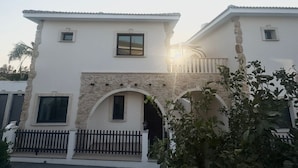 Un edificio de dos plantas con fachada blanca, detalles de piedra y una entrada central en arco.