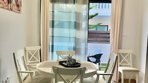 Un comedor con una mesa redonda, sillas blancas y una bandeja con una cafetera y tazas.